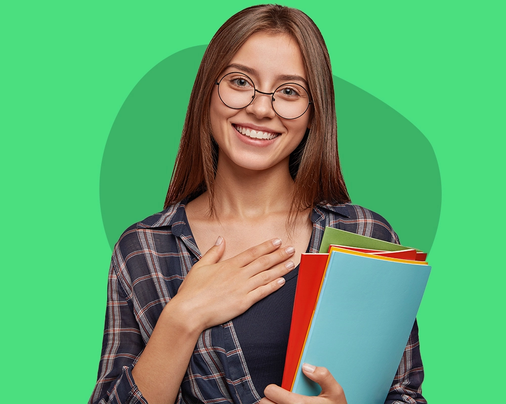 Mujer joven sonriente con gafas sosteniendo cuadernos y haciendo un gesto de gratitud y alivio